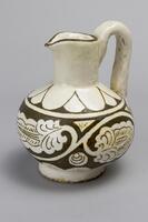 Cream colored pitcher with brown decoration and white handle.