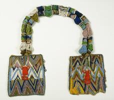 A necklace composed of two beaded, square panels joined by a double strand of clusters of beads. The double strand joining the panels consists of beads in shades of green, blue, pink, yellow, and white. The square panels are decorated with zig-zag patterns in various colors and feature a face in the center, made of red beads. 