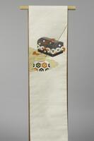 <p>Off-white and gold speckled Nagoya Obi with various&nbsp; interwoven gray gold, gray, orange, and green motifs. The interwoven motifs consist of a gold cloud background on which a treasure box decorated with violet, orange, and green seigaiha (wave crest) motif patterning and a vase decorated with hexagonal orange, green, and navy blue paulownia leaf motif patterning, a fishing rod, and water ripple motifs, and gunbai uchiwa (fan held by sumo wrestler referee) are depicted to possibly narrate the Urashima Tarou tale.</p>
