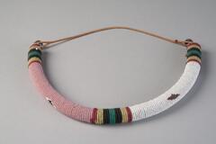 Necklace made of beads in white, pink, yellow, red, green and black. Half of the neckace is string, which goes around the neck.