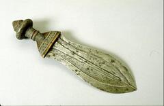 Knife with leaf-shaped blade and wooden handle. The blade is engraved with several lines running along the length of the blade, while the handle has various geometric patterns and lines carved in it. 