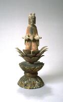 The figure is kneeling musician on lotus seat, made of separately carved petals. Below the seat, there is a base, which consists of two lotus-shaped half-sphere, connected up-side-down. The head has two buns, elongated ears, simplified facial parts; the figure wears a pink robe with wide sleeves, holding a sort of instrument with hands.