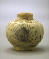 A small, stoneware jar of squat proportions, with a narrow, upright neck and a short, cylindricrical foot. The jar is decorated with loosely drawn floral patterns in cobalt blue underneath an overalll whitish glaze.<br />
This jar makes an interesting contrast to 2002/2.18, which has a very similar design in a crisp, dark blue; the faded, smudged blue here may be a result of less than ideal conditions in the kiln.
