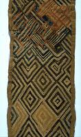 Rectangular panel with tan hemmed edges. The design consists of a grid of multiple diamonds and chevrons. Several of the lines at the top of panel are burnt sienna and blue in color.