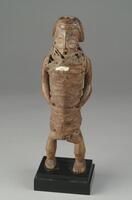 This carved wooden figure depicts a standing male, and is one of a pair that includes a female figure also carved by the same hand. According to noted art historian Niangi Batulukisi, these two figures deviate from the classical Bembe style and are “an extreme rarity” due to the fact that they are likely connected to an ancient pre-Bembe style.<br /><br />
The male figure’s trunk is disproportionately long, while the legs are slightly flexed at the knees. His facial features includes closed eyes set in round, ocular cavities and a perfectly rounded, open mouth.  The hairstyle bears geometric motifs. Most striking, however, is that medicinal substances have been tied around the male’s entire torso--indeed from his neck to his pelvis--by tightly-wound, resin-covered strings. Moreover, a hole appears on the crown of his head, likely intended for the placement of an animal horn containing even more medicinal ingredients. A small sliver of a white shell appears across the figure’s chest. Traces of tukula powder ca