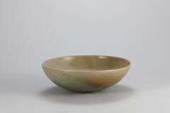 <p>The inner surface of this bowl features an incised design of two parrots with long tails resembling phoenixes. e entire body of the bowl was glazed including the rim of the foot, on which remain three quartzite spur marks. Although some fireclay has fallen inside the kiln during ring and adhered to the inner surface of the bowl, the state of sintering is good. The piece as a whole is a high-quality ware with a glossy surface and a fine color of glaze. The base of the foot is cracked which occurred while drying before the application of glaze.<br />
[<em>Korean Collection, University of Michigan Museum of Art </em>(2014) p.94]</p>
high quality, incised, double-parrot motif shallow bowl, nice shallow fully glazed foot, three spur marks, firing discoloration, kiln trash fall on glaze, 11th century.