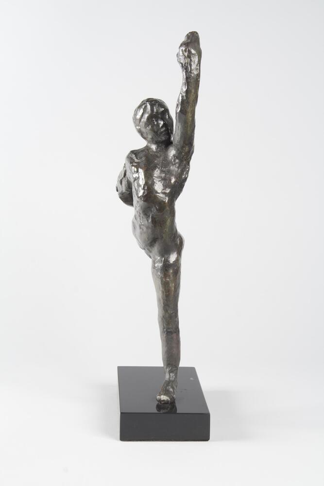 A bronze sculpture of a dancer. The dancer is shown in a front kick with their right leg.