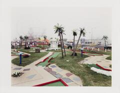 Image of a minigolf course with a carnival in the left background with the Stone Pony music venue on the right. 