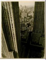 This photograph depicts a bird's eye view of Manhattan, framed by the towers of the Rockefeller RCA building and the International Building. In the center of the frame is located the construction site for the Rockefeller Associated Press building.