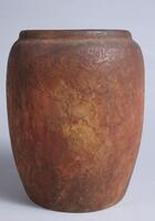 Wide cylindrical footless vessel with slightly bowed side, small rim and very large mouth covered with a textured matte glaze in shades of light and dark browns<br />