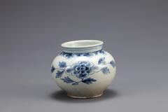 This small jar features large peony sprays in the center of the body, and above them are decorated a yeoui-head band. This type of the small blue-and-white porcelain jars was popular among collectors thanks to the outstanding harmony of white and blue. This piece has coarse sand spur marks, and red spots are visible on the foot rim. The jar remains intact, and the glaze was well fused.<br />
[Korean Collection, University of Michigan Museum of Art (2014) p.173]