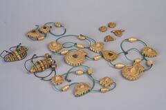 Multiple pieces of straw jewelry. Some have strands of bright blue beads with them and others are on brown string.