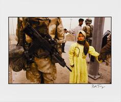 A color photograph featuring a soldier&#39;s back on the left, rifle prominent, and a young girl in a yellow dress on the right. She holds a hand and stares at the viewer. In the background, a man holds his arms up in front of another soldier.