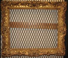 A wooden frame in gold color decorated with gold leaf pattern.