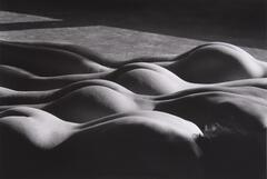 This photograph shows four nude figures lying prone, their forms repeating in a diagonal across the frame.