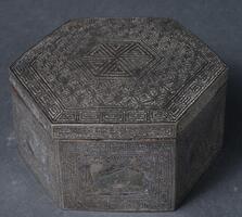 Inlaying silver into ironware was a popular method of decorating metalwork that required high levels of skill. Numerous items were produced with inlay decorations. The entire lid and body of this hexagonal case are decorated with inlaid silver. The lid features a hexagonal design in its center surrounded by a continuous four-leaf flower design. The six sides of the body are decorated by three pairs of turtle designs, crane designs and deer designs, arranged alternately. The lid and body are bordered with a fret-patterned band. This case with a flat base is excellently preserved. This type of iron-lidded case with inlaid silver design was produced in large quantities from the nineteenth century to the early twentieth century, continuing through the Japanese annexation of the Korean Peninsula. Such cases are mostly octagonal; this is a rare hexagonal example.
<p>[Korean Collection, University of Michigan Museum of Art (2017), 244]</p>
