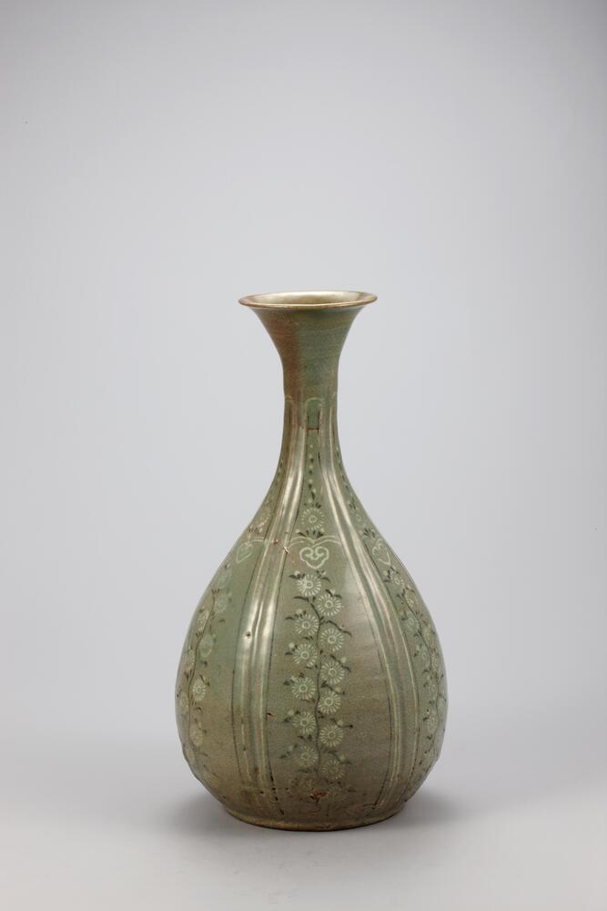 <p>This vessel was produced in a form typical of 13th century celadon bottles with the beautifully curved form and inlaid decorations on the entire surface. The body is divided into six segments, each of which is inlaid with chrysanthemum stems rst then stamped with owers using the inhwa (stamping) technique. Glaze was wiped away from the base and sand supports were used during ring. Glaze on the lower part of the bottle was poorly fused, yielding an opaque surface, however the overall quality of sintering is fine. The mouth has been repaired and restored. This piece is assumed to have been produced at a kiln at Yucheon-ri, Buan-gun, Jeollabuk-do.<br />
[<em>Korean Collection, University of Michigan Museum of Art</em> (2014) p.136]</p>
