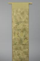 <p>textured gold and pale green fukuro (single-sided) obi with embroidered camouflage-dyed paper-like material within a triangular grid and gold modified sauvastika (reverse swastika) motif patterning called &ldquo;sayagata&rdquo; in Japanese embroidered within patched gold-embroidered floral foliage motifs.</p>
