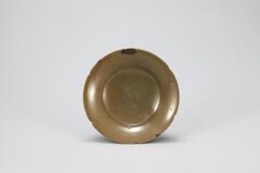 <p>This olive-brown colored dish is of the finest quality, made from carefully selected clay and glaze. This dish provides a good illustration of the forms and production standards of celadon from the first half of the Goryeo period. The walls are thick, but the use of fine clay has produced a robust texture. The glaze was thinly applied, thus yielding opaque and smooth surface, similar to that of the 10th century Chinese Yue celadon. Its rim is shaped as six flower petals and repaired in three parts. Many vessels in this form were produced around Yongun-ri, Gangjin-gun, Jeollanam-do.<br />
[<em>Korean Collection, University of Michigan Museum of Art</em> (2014) p.</p>
<br />
An olive-brown dish with thick walls and a robust texture. The galze is thing, creating an opaque and smooth surface. The rim is shaped like six flower petals and has been repaired in three places.