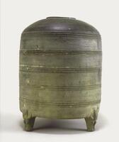 A gray earthenware cylindrical granary, with bowstring decoration around the body, a domed lid with a circular opening, and three bear-shaped feet.