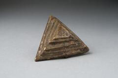 Gold-weight in the shape of a triangular base with four stepped triangles. 