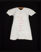 Child&#39;s dress embroidered with the words &quot;you will be made to feel dumb again and again&quot; in red thread and contained within a black shadowbox.&nbsp;