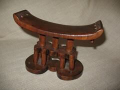 Zimbabwe, with geometric forms.<br />
Headrests are small furnishings, typically sculpted from wood. They frequently have a concave platform supported by legs, though the platform can also be flat and/or be supported by a central post that may be connected to a broad base. The platform may be cushioned to provide comfort for the owner&rsquo;s head, and many headrests feature complex ornamentation and sculptural details. Headrests share some of the same motifs and associations with stools, as they are constructed similarly and used for similar purposes.