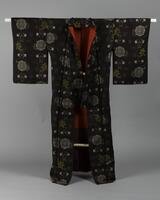 <p>dark brown komon Ooshima tsumugi kimono with an interwoven arrangement of blue, white, and green autumnal foliage with a red and maroon inner lining.</p>
