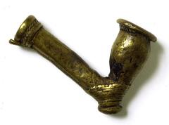 A cast brass pipe bowl with a leaf design around the stem end and a design of horizontal grooves around the bottom, near the small round base. 