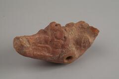 Indian terracotta figure in abstract form, partly eroded. There is a hold at the bottom of the figure/