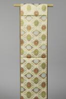 <p>Pale yellow fukuro (single-sided) Obi with interwoven modified sauvastika (reverse swastika) motif patternings called &ldquo;sayagata&rdquo; in Japanese,&nbsp; and off-white interlocking oval patterning with white, red, and green chrysanthemum and paulownia leaf motifs on one side and only gold sayagata motifs on the reverse side.</p>
