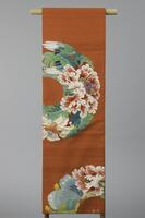<p>Dark orange fukuro (single-sided) Obi with brocading of green, aqua, and silver, gold bird and butterfly and pink peonies and chrysanthemums arranged in a wreath shape. There may be a signature of the artist interwoven in gold on one of the ends in old Chinese characters.</p>
