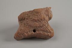 Terracotta fragment carved on one side with an intricate patters of lines. There is a small hole on the bottom of the patterned side of the piece that does not go all the way through to the undecorated side.