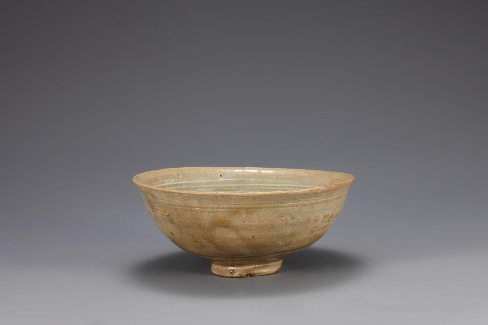 <p>The decoration technique of stamping designs into vessel&rsquo;s surface and filling them with a white slip was continued from Goryeo celadon to buncheong ware. Three or four horizontal lines of chrysanthemum run around the rim. There are three spur marks on the inner base: this is the result of stacking vessels on top of one another during ring, separated by supports. Coarse grains of sand are stuck on the outer base and foot. The clay used for this bowl is fine and contains small amount of sand, while the glaze is pale green in color and well fused. Despite having become warped in the kiln, this bowl well illustrates the crude yet solid characteristics of buncheong ware.<br />
[Korean Collection, University of Michigan Museum of Art (2014) p.146]</p>
